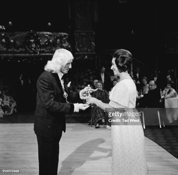 English DJ Jimmy Savile receives the Carl Alan award for top disc jockey of 1969 from Princess Margaret at the Lyceum Ballroom in London, 18th March...