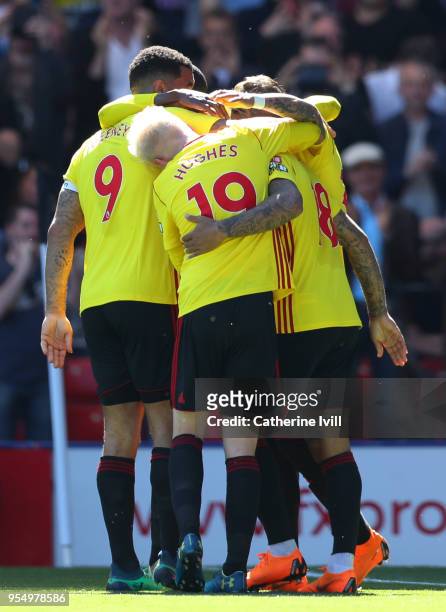 Andre Gray of Watford celebrates scoring his side's second goal with team mates Will Hughes and Troy Deeney during the Premier League match between...