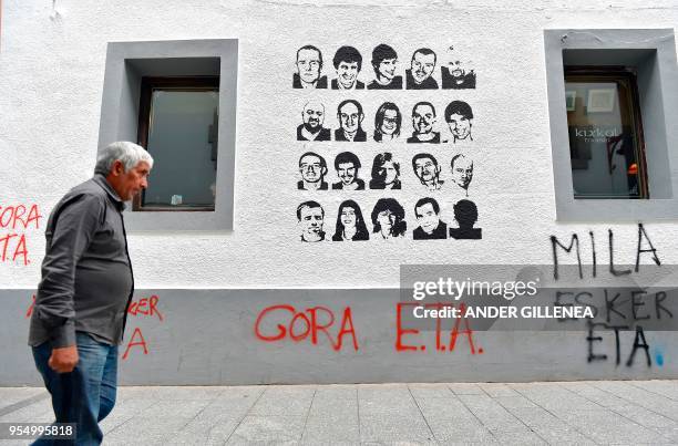 Man walks past a graffiti depicting portraits of Basque separatist group ETA prisoners and reading "Long life ETA, thanks a lot" in the Spanish...