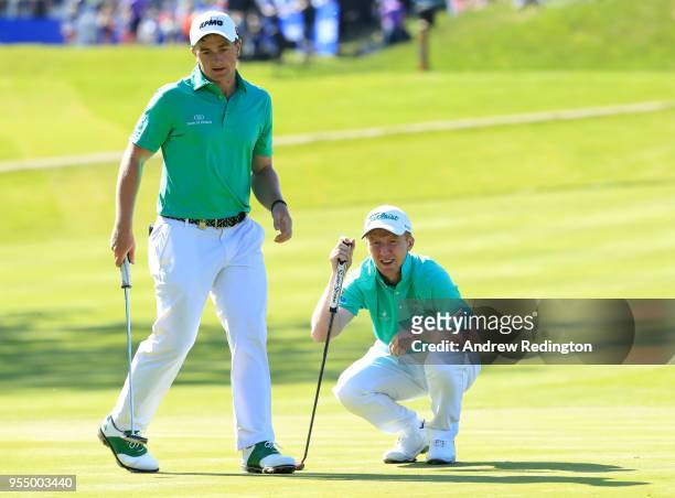 Gavin Moynihan of Ireland lines up a putt as Paul Dunne of Ireland looks on the first green during Day One of the GolfSixes at The Centurion Club on...