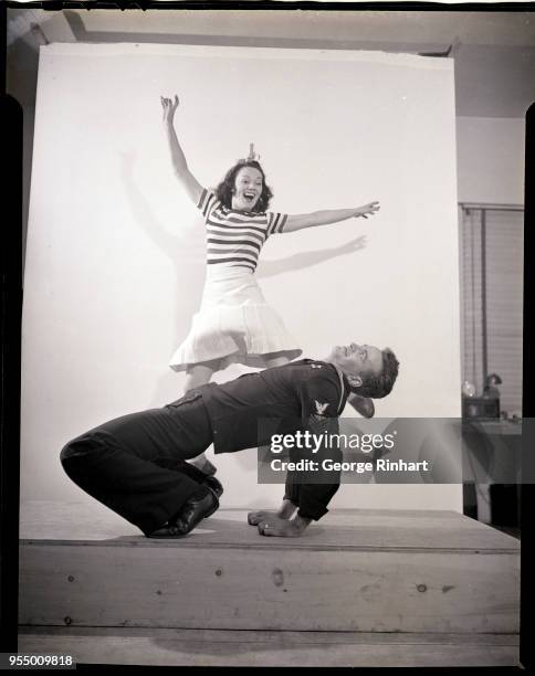 Sailor and woman dancing the jitterbug, A sailor and a woman are shown jitterbugging. He is bent over backwards on the floor, while she is leaping in...