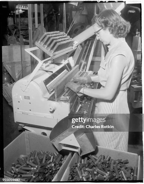 Inspection of shotgun shell casings, A worker inspects shotgun shell casings in the ammunition division of East Alton Works. Location: East Alton,...