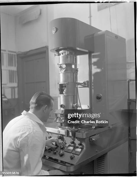 Worker using an electronic microscope, A worker in the electrical division of the East Alton Works plant uses an electronic microscope for battery...