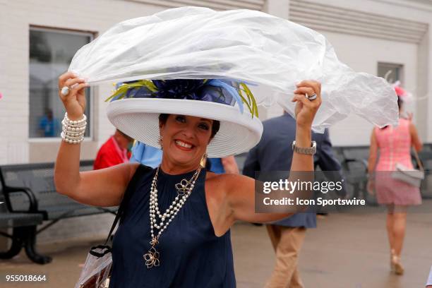 Derby fan tries to protect her hat from the rain during the 144th running of the Kentucky Derby at Churchill Downs on May 5th, 2018 in Louisville,...