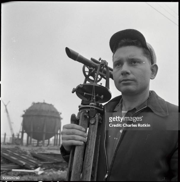 Surveyor at site of ammonia plant, A surveyor at a Texaco refinery takes measurements at the construction site of an ammonia plant, circa 1957,...