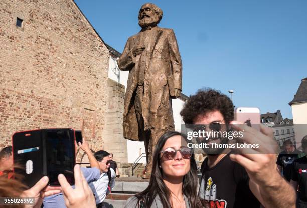 Visitors take pictures in front of sculpture of German philosopher and revolutionary Karl Marx on the 200th anniversary of the birth of Karl Marx on...