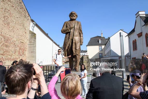 Visitors take picutres in front of sculpture of German philosopher and revolutionary Karl Marx on the 200th anniversary of the birth of Karl Marx on...