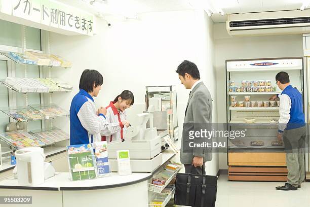 businessman at checkout counter - コンビニ ストックフォトと画像