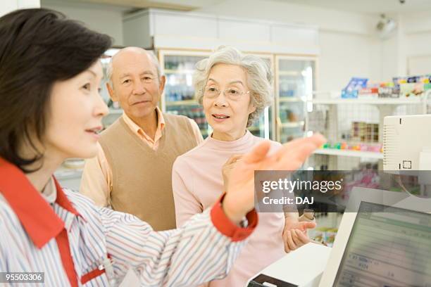 senior couple asking cashier for direction - キャッシュレジスター ストックフォトと画像