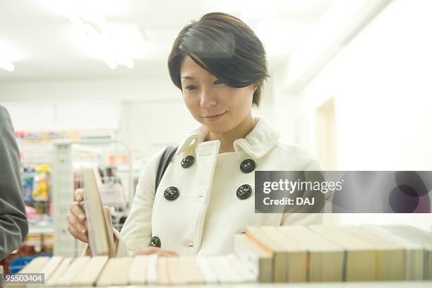 young woman reading book at convenience store - quartier d'itabashi photos et images de collection