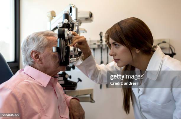 female optometrist using a phoropter on senior patient - astigmatism stock pictures, royalty-free photos & images
