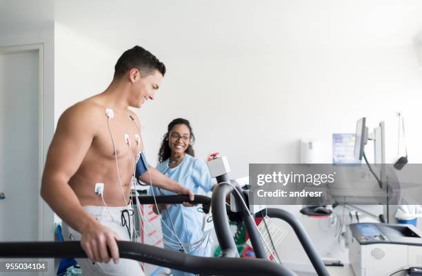 bella infermiera afroamericana che monitora un allegro paziente maschio che fa uno stress test - heartbeat foto e immagini stock