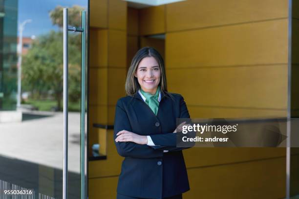 latin american donna direttore dell'hotel in piedi all'ingresso con le braccia incrociate guardando la fotocamera molto felice - concierge foto e immagini stock