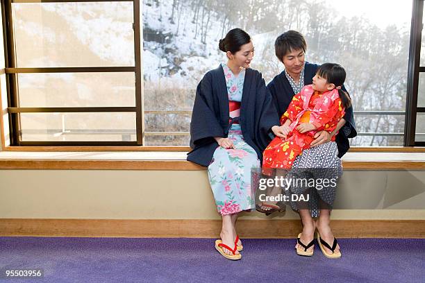 family in yukata sitting beside the window, smiling - kimono winter stock pictures, royalty-free photos & images