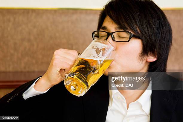 young man drinking beer - サラリーマン 酒 ストックフォトと画像