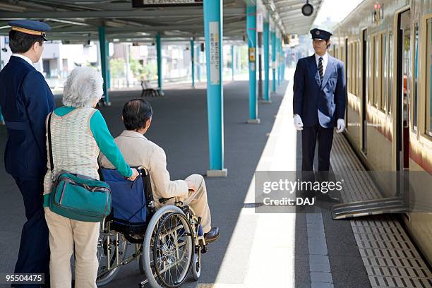 conductors and senior couple at platform, senior man in wheelchair - conductor ストックフォトと画像