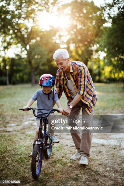 junge mit dem fahrrad mit opa im park - fahrrad fahren großeltern mit kind stock-fotos und bilder