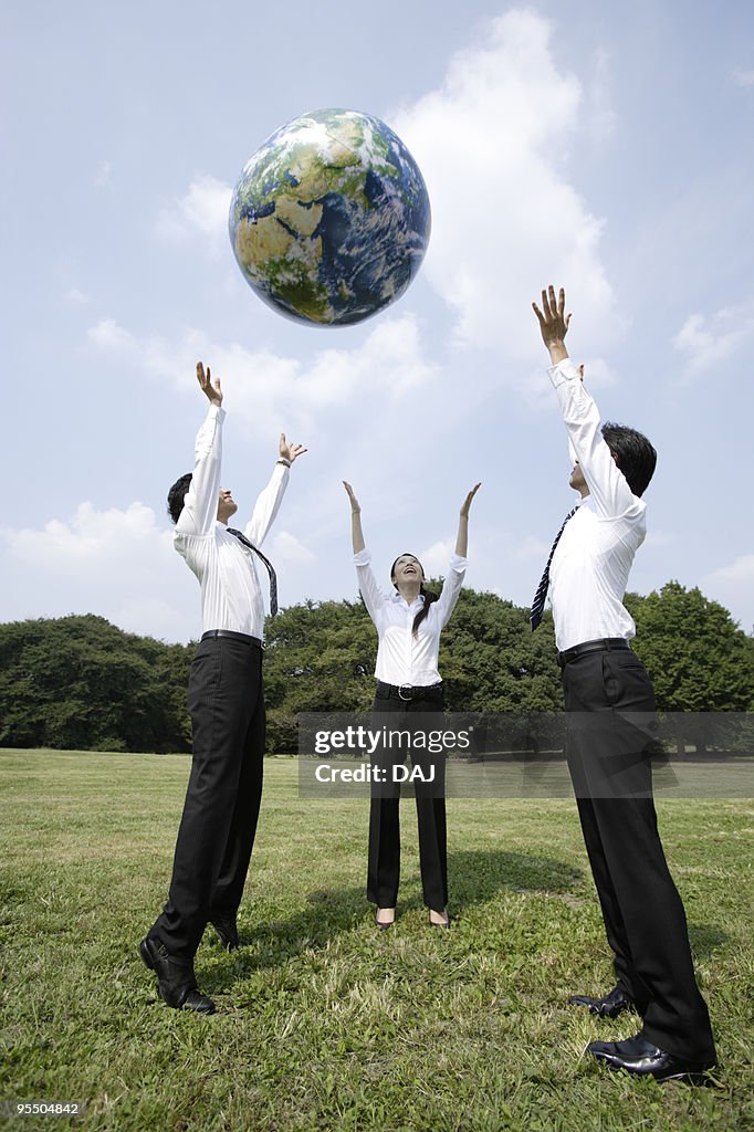 Businesspeople Throwing An Earth Ball Into The Air