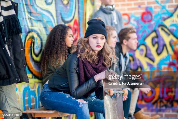 十代の少女はスケート ボードとストイックに座っています。 - clique ストックフォトと画像