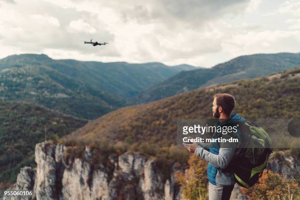 excursionista en la cima de la montaña volando un drone para hacer videos y fotos - punto de vista de dron fotografías e imágenes de stock