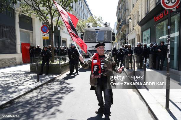 Protester waves a flag of "Che Guevara" in front of riot police officers, during a protest dubbed a "Party for Macron" against the policies of the...