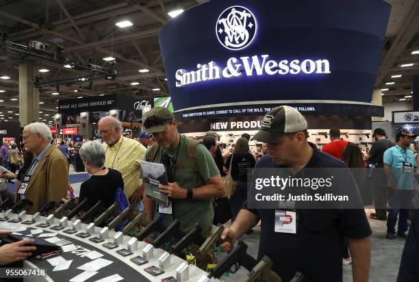 Attendees look at a display of Smith and Wesson handguns during the NRA Annual Meeting & Exhibits at the Kay Bailey Hutchison Convention Center on...