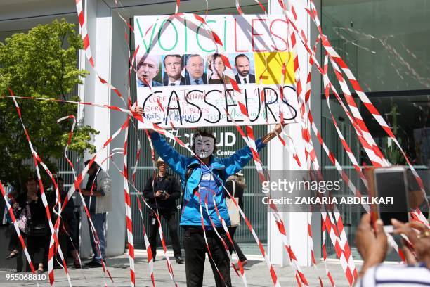 French activist Jean-Baptiste Redde, aka Voltuan holds a placard depicting the French president and ministers and reading "here are the...
