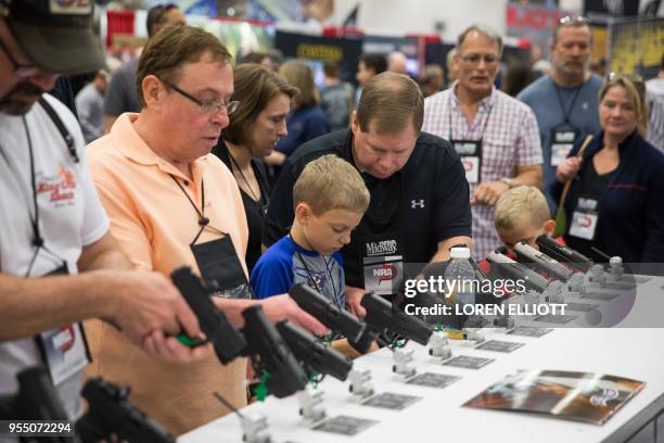 People browse firearms in an exhibit hall at the NRA's annual convention on Saturday, May 5, 2018 in Dallas, Texas.