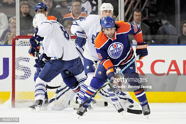 Zack Stortini of the Edmonton Oilers tries to deflect the puck in front of Mike Komisarek of the Toronto Maple Leafs and Tomas Kaberle in the first...