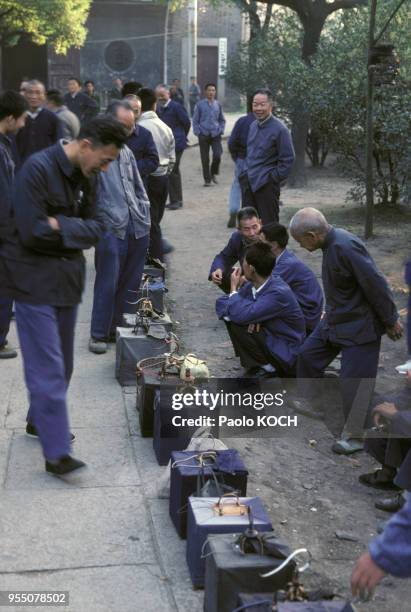 Habitants ammenant leurs canaris dans un parc pour les faire chanter, à Hangzhou, en octobre 1979, Chine.