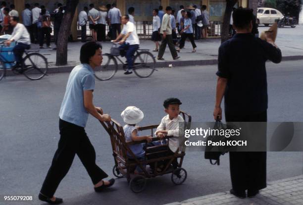 Enfants dans une poussette en bois à Pékin, circa 1970, Chine.