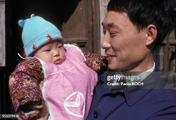 Homme tenant son bébé dans les bras à Nankin, circa 1970, Chine.