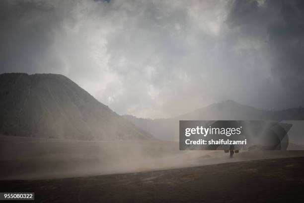 unidentified local people of tengger walking in sandstorm at savanna of tengger caldera, mt. bromo, east java of indonesia. - mt semeru stock-fotos und bilder