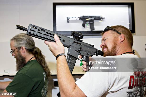An attendee holds a Sig Sauer Inc. Rifle at the company's booth during the National Rifle Association annual meeting in Dallas, Texas, U.S., on...