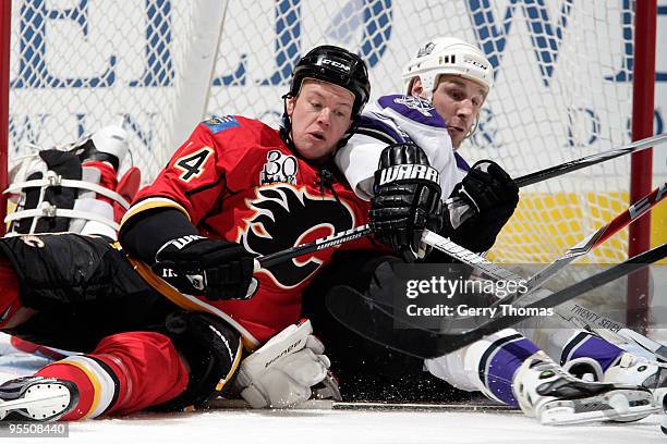 Aaron Johnson falls on top of Miikka Kiprusoff of the Calgary Flames with Ryan Smyth of the Los Angeles Kings on December 30, 2009 at Pengrowth...