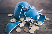 shattered broken piggy bank with coins on rustic wooden table