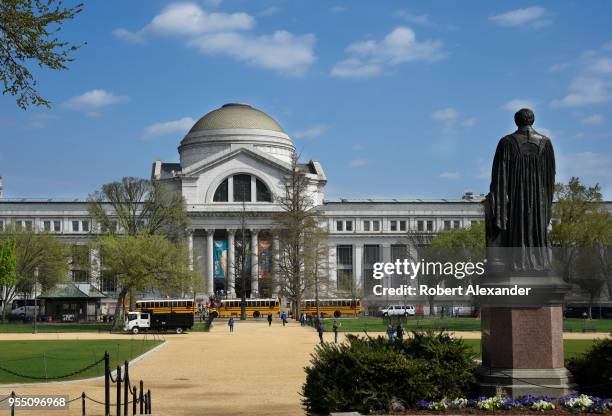 School buses unload visiting students in front of the National Museum of Natural History in Washington, D.C. Facing the museum is a statue of the...