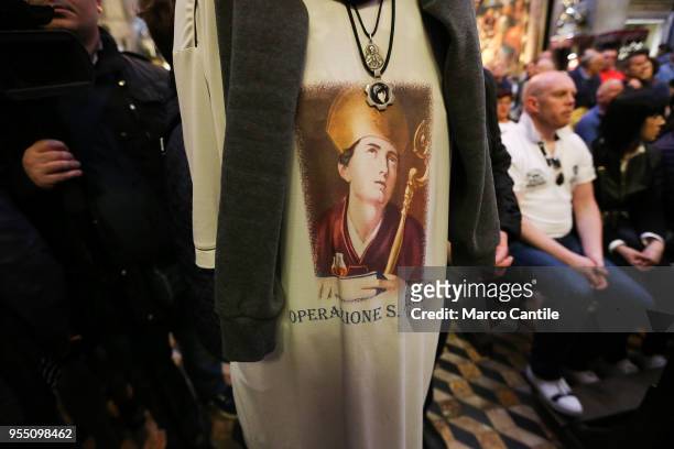 Man in a t-shirt with the image of San Gennaro prays before the procession of the patron saint in the streets of Naples.