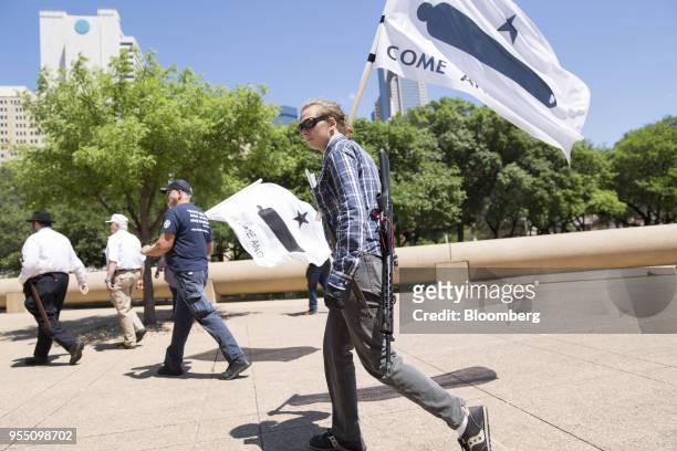 Demonstrator open carries a rifle while holding a flag during a pro-gun rally on the sidelines of the National Rifle Association annual meeting in...