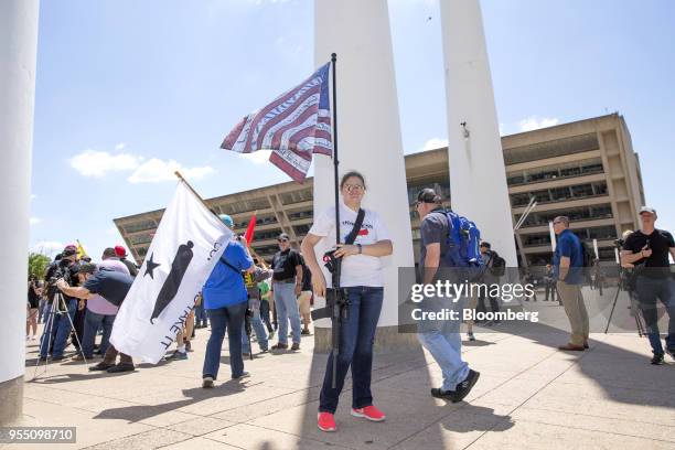 Demonstrator open carries a rifle while holding an American flag during a pro-gun rally on the sidelines of the National Rifle Association annual...