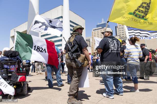 Demonstrators open carry rifles while holding flags during a pro-gun rally on the sidelines of the National Rifle Association annual meeting in...