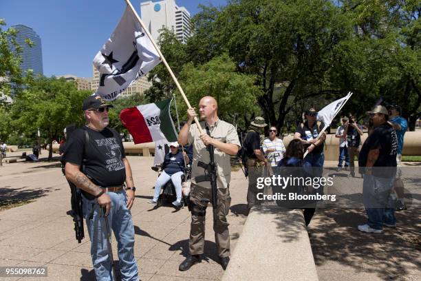 Demonstrators open carry rifles while holding flags during a pro-gun rally on the sidelines of the National Rifle Association annual meeting in...
