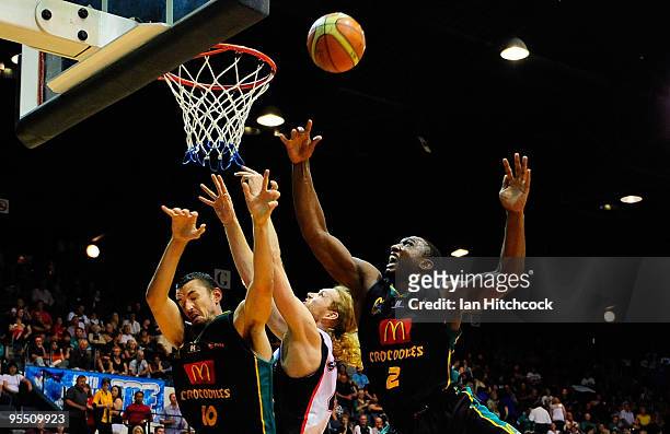 Rolen Roberts looks to grab a rebound with Russell Hinder of the Crocodiles and Luke Schenscher of te Wildcats during the round 14 NBL match between...