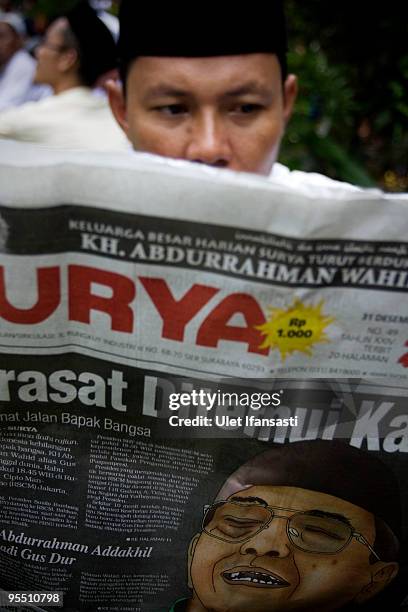 Man reads a newspaper featuring a headline on Abdurrahman Wahid's death during the State funeral for former Indonesia president Abdurrahman Wahid in...