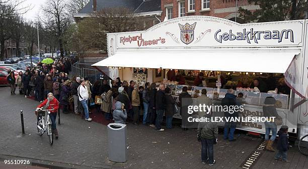 People gather at a stand selling Oliebollen, a doughnut like pastry, in Rotterdam on December 31, 2009. Oliebollen is traditionally made and consumed...