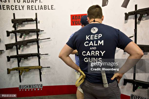 Attendees browse Bushmaster Firearms International LLC rifles at the company's booth during the National Rifle Association annual meeting in Dallas,...