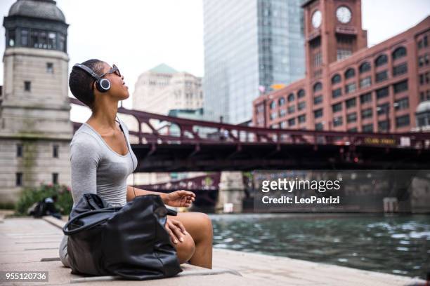 woman in the city listening to music and chilling out in chicago downtown - chicago: the musical stock pictures, royalty-free photos & images
