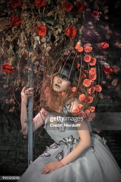 romantic girl into birdcage embracing treelike floristic composition - treelike stock pictures, royalty-free photos & images