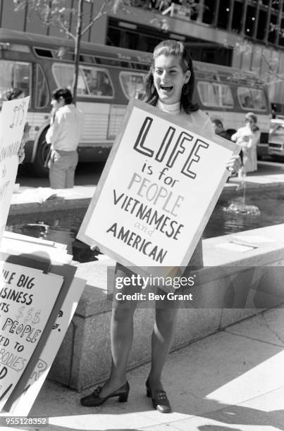 Portrait of young woman as she holds a sign that reads 'Life is for people, Vietnamese and American' outside the Time Life Building during the...