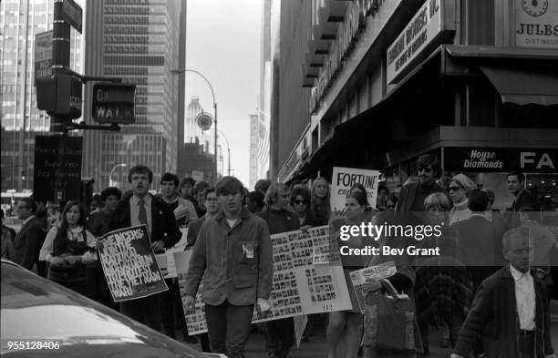 View of demonstrators, among pedestrians, as they cross 49th Street on 6th Avenue during the Moratorium to End the War in Vietnam demonstration, New...